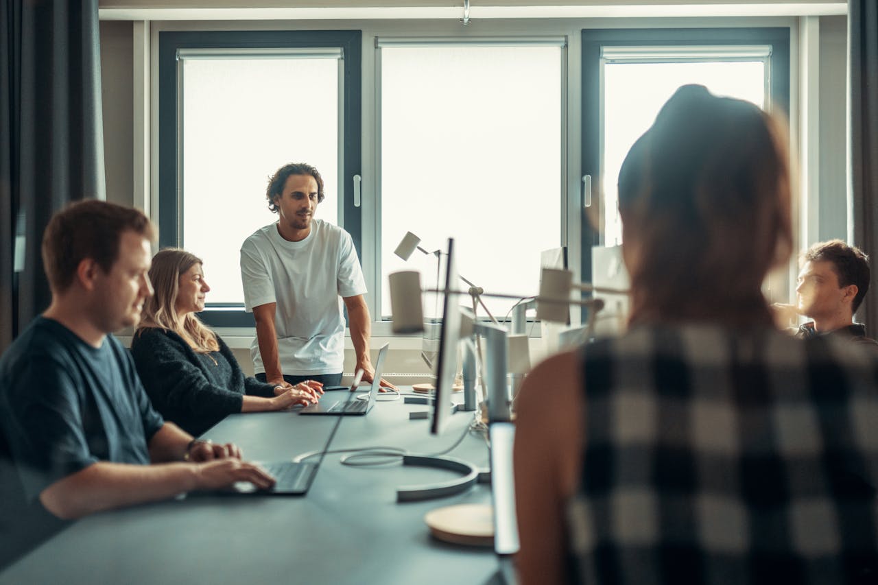 about-img A diverse team engaged in discussion during a collaborative office meeting.